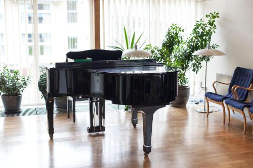 a black piano in a room with plants at STF Wendelsberg Hotel & Hostel in Mölnlycke