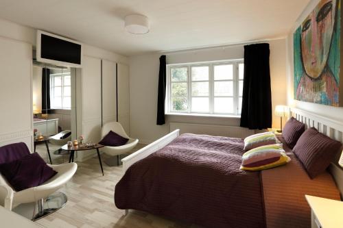 a bedroom with a bed and a chair and a window at Aars Hotel in Års