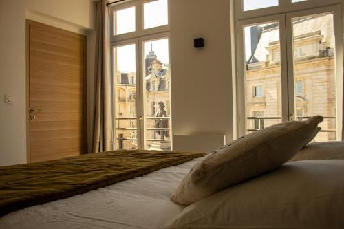 une chambre avec un grand lit avec une grande fenêtre dans l'établissement Suite Charles - 2 pers chic & intemporelle, à Charleville-Mézières