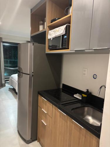 Una cocina con frigorífico de acero inoxidable y fregadero. en Frente Mar Salvador Bahia, en Salvador