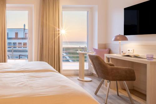 ノルダーナイにあるHotel Stranddistelのベッドと机と窓があるホテルの部屋