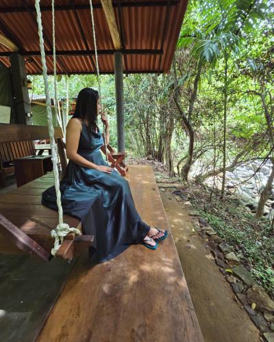 a woman sitting on a swing talking on a cell phone at Powerhouse River Resort in Eheliyagoda
