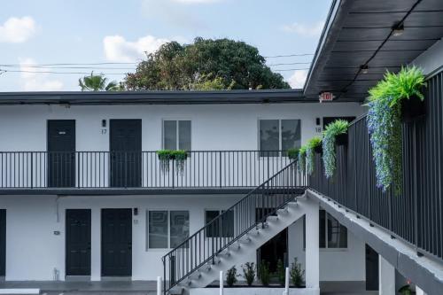 an exterior view of a white building with black doors and plants at The Jaxon in West Palm Beach