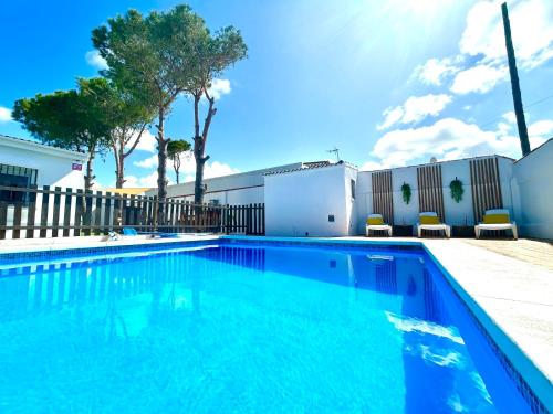 a swimming pool with blue water in front of a fence at GATU Villa Serena piscina privada mayores de 25 años y familias in Chiclana de la Frontera