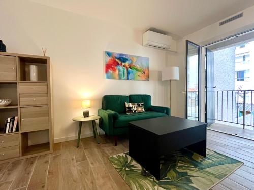un salon avec un canapé vert et une table dans l'établissement Charmant T2 proche plages, climatisation et balcon, à Six-Fours-les-Plages