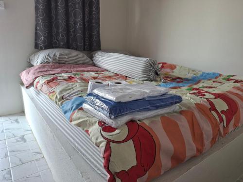 Ban Lao Suan Kluaiเอสบีพูลวิลล่า的一张凌乱的床，上面铺着毯子和枕头