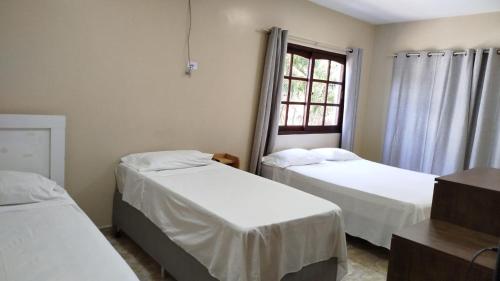 a bedroom with two beds and a window at Suites da Gladys in Foz do Iguaçu