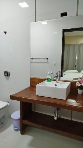 a bathroom with a white sink and a mirror at Suites da Gladys in Foz do Iguaçu