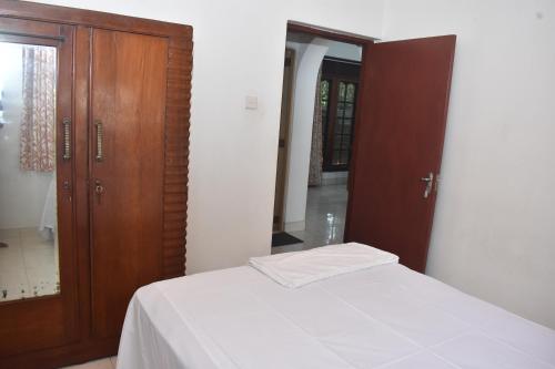 a bedroom with a bed and a wooden cabinet at Peradeniya-Kandy Home Stay in Peradeniya
