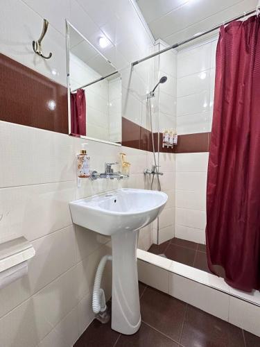 a bathroom with a sink and a red shower curtain at Hotel New Terrace in Tbilisi City