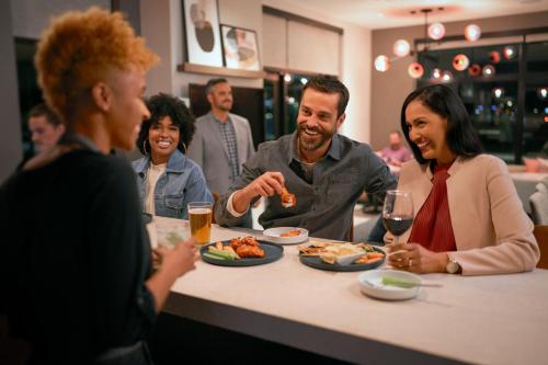 a group of people sitting around a table eating food at Atwell Suites - DENVER AIRPORT TOWER ROAD by IHG in Denver