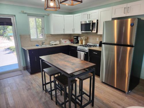 a kitchen with a stainless steel refrigerator and a table at By The Bay Rentals Rock Sound in Rock Sound