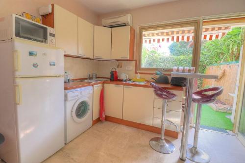 La cuisine est équipée d'un réfrigérateur blanc et d'un lave-vaisselle. dans l'établissement Charmant studio avec jardin, à Antibes