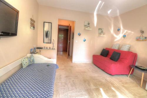 un salon avec un canapé rouge et une télévision dans l'établissement Charmant studio avec jardin, à Antibes