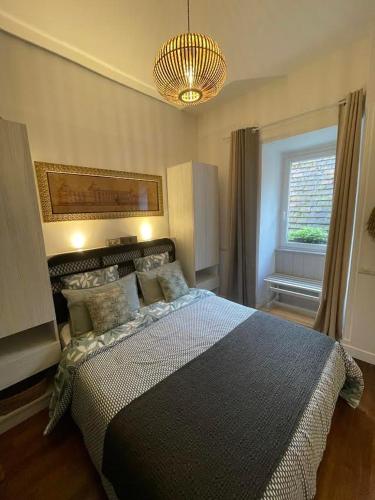 une chambre avec un grand lit et un lustre dans l'établissement Appartement La Couronne Sarlat-La-Canéda, à Sarlat-la-Canéda