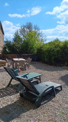 a patio with a picnic table and a table and chairs at Le gîte vouté confort et repos in Saint-Beauzély