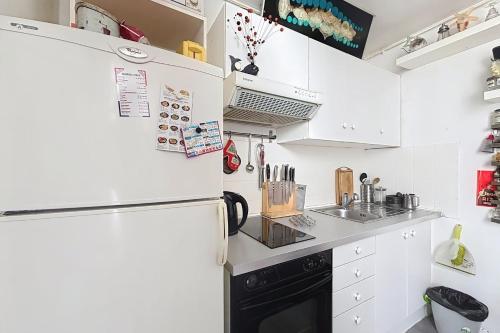  La cuisine est équipée de placards blancs et d'un réfrigérateur. dans l'établissement Charming 2-room apartment near Montmartre, à Paris