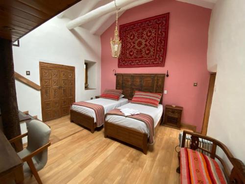 two beds in a room with pink walls and wooden floors at Artinka Boutique Hotel in Cusco