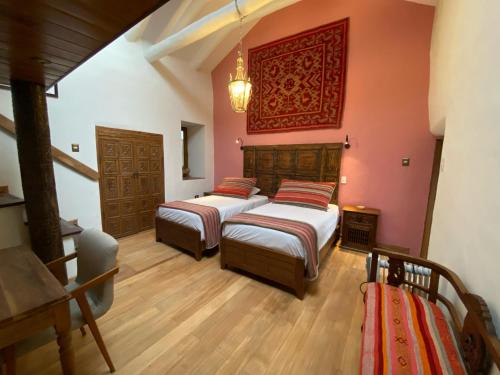 two beds in a room with pink walls and wooden floors at Artinka Boutique Hotel in Cusco