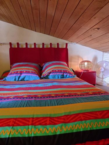 - un lit avec une couette colorée à rayures et 2 oreillers dans l'établissement Les MIMOSAS Gîte du Mas Haut, à Saint-Jean-du-Gard