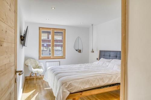 a bedroom with a large bed and a chair at Huxa Appt Megève Centre in Megève