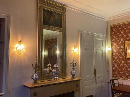 Una habitación con un espejo y una mesa con jarrones. en Château De La Coutancière, en Brain-sur-Allonnes