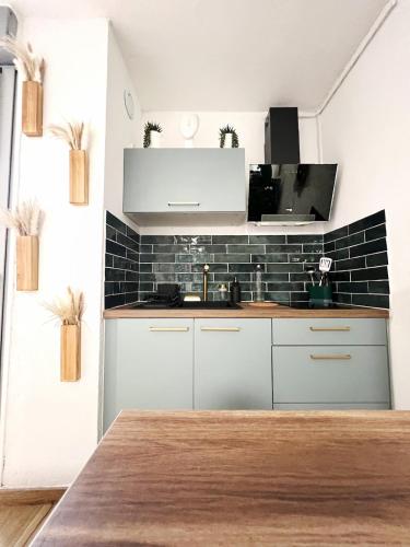 Il comprend une cuisine avec des placards blancs et un mur en carrelage noir. dans l'établissement Le COSY BALI Studio lumineux, à La Grande Motte