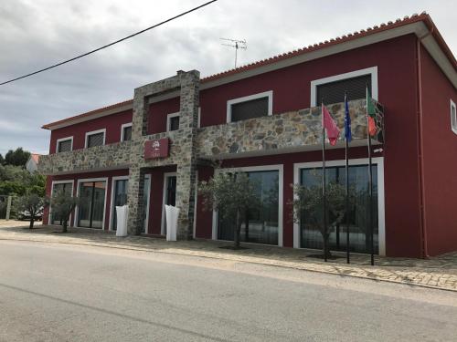a red building with flags in front of it at Hotel Rural da Catraia in Chão Redondo