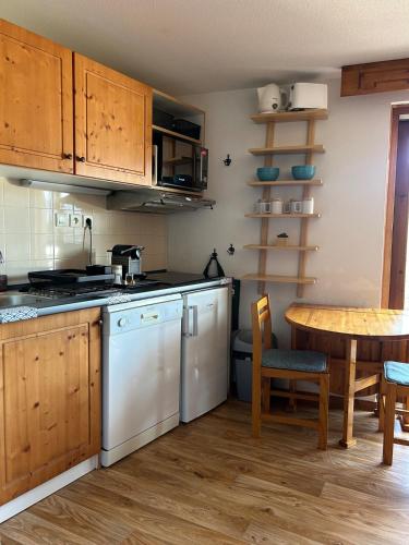 - une cuisine avec des placards en bois, une table, une table et des chaises dans l'établissement Appartement Chamrousse, à Chamrousse