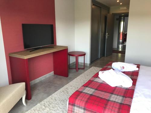 a room with a tv and a bed with a red wall at Hotel Rural da Catraia in Chão Redondo