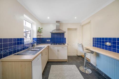 a kitchen with blue tiles on the walls and a sink at Beautiful Large Bedrooms in South Norwood