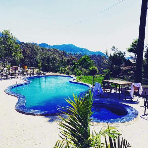 a large swimming pool with a table and chairs at Paradise Pool Resort in Nainital