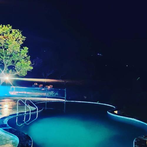 a swimming pool at night with blue water at Paradise Pool Resort in Nainital