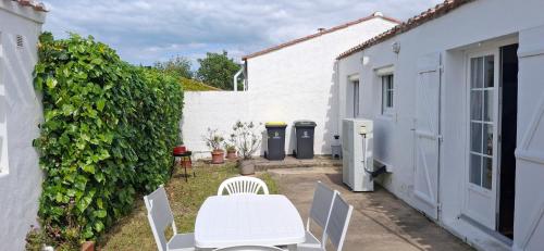 un patio avec une table et des chaises à côté d'un bâtiment dans l'établissement Maison familiale à 600 m de la plage, à Barbâtre