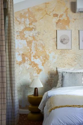 une chambre avec un lit et un mur en pierre dans l'établissement Casaïa - La Cigale - Chambre avec salle de bain privée, à Hyères