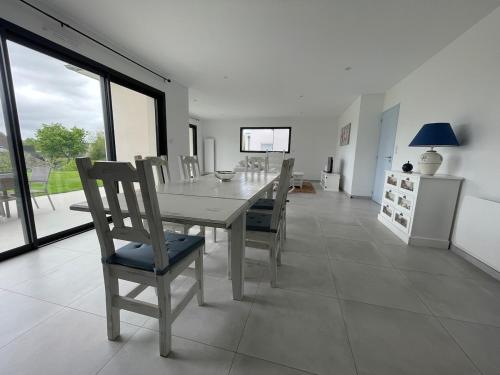 une salle à manger blanche avec une table et des chaises dans l'établissement Maison récente bord de mer Binic, à Binic