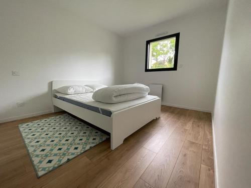 une chambre blanche avec un lit et une fenêtre dans l'établissement Maison récente bord de mer Binic, à Binic