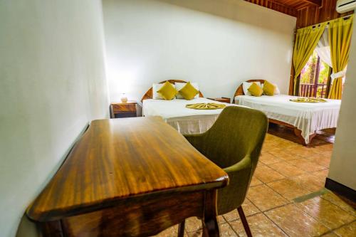 a room with two beds and a wooden table at Poshtel Arenal in Fortuna