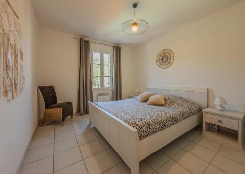 a bedroom with a bed and a chair and a window at Nouveauté, maison avec piscine in Collobrières