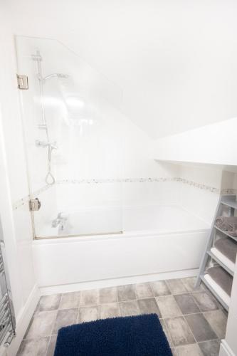 a bathroom with a tub and a blue rug at Cosy Llandudno Apartments in Llandudno