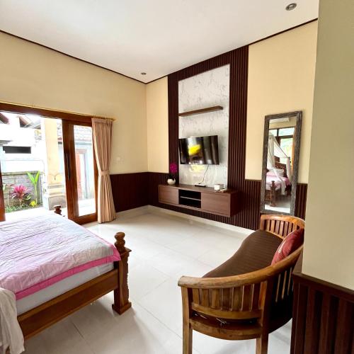 a bedroom with a bed and a tv and a mirror at Dodit House in Ubud
