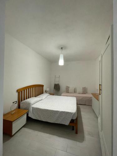 a white bedroom with a bed and a nightstand and a bed sidx sidx sidx at La casa di Nenni in Santa Giusta