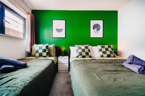 zwei Betten in einem Zimmer mit grüner Wand in der Unterkunft Trendy Accommodation in Arsenal in London