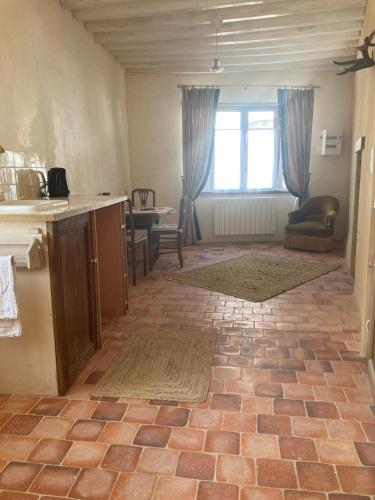 a kitchen with a counter and a table and a window at Sur Les Ailes du Papillon-Le Duplex in Saint-Sauveur-en-Puisaye