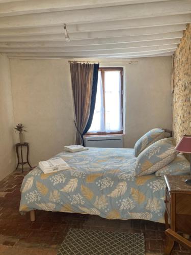 a bedroom with a bed with a blue comforter and a window at Sur Les Ailes du Papillon-Le Duplex in Saint-Sauveur-en-Puisaye