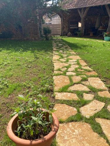 a stone pathway in a yard with a potted plant at Sur Les Ailes du Papillon-Le Duplex in Saint-Sauveur-en-Puisaye
