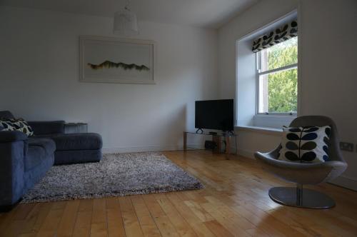 a living room with a couch and a television at Chaucer View, Chaucer House Apts in Keswick