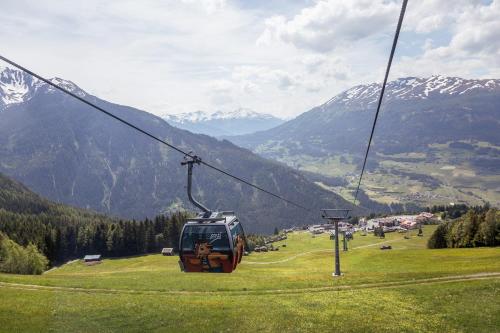 a ski lift in a field of grass with mountains at Appartement Pitztal-Hochzeiger inclusive Pitztal-Sommer Card in Jerzens