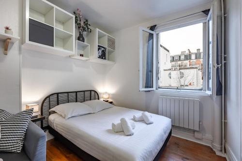 une chambre avec un lit avec des draps blancs et une fenêtre dans l'établissement Cozy studio near Montparnasse, à Paris