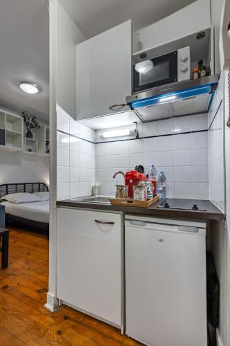une petite cuisine avec des armoires blanches et un évier dans l'établissement Cozy studio near Montparnasse, à Paris